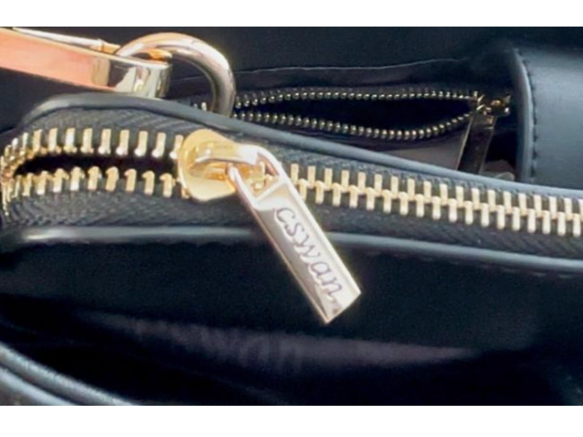 Close-up of Black CSWAN handbag showing gold-tone hardware and engraved zipper detail
